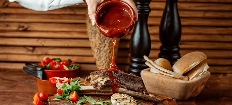 Pouring bbq sauce on meat